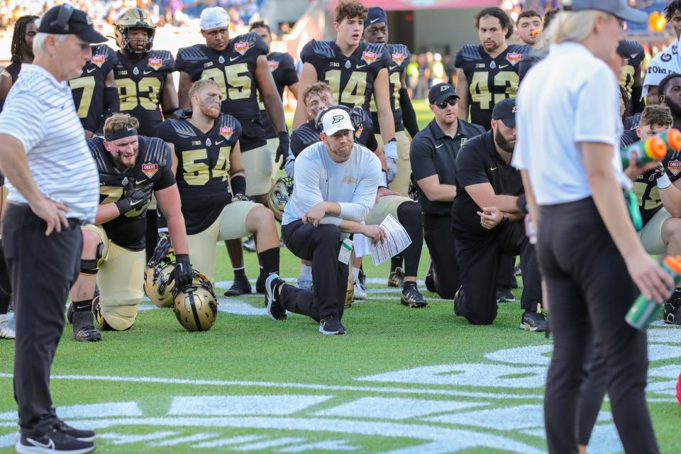 Jan 2, 2023; Orlando, FL, USA; Purdue Boilermakers head coach Ryan Walters and team take a knee while injured wide receiver Deion Burks (not pictured) is tended to during the second half at Camping World Stadium.