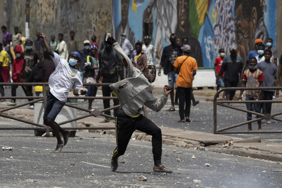 Demonstrators throw rocks at riot policemen during protests against the arrest of opposition leader and former presidential candidate Ousmane Sonko in Dakar, Senegal, Friday, March 5, 2021. Days of violent protests in Senegal have killed at least one person, local reports say, as young people take to the streets nationwide in support of the main opposition leader who was detained Wednesday. (AP Photo/Leo Correa)