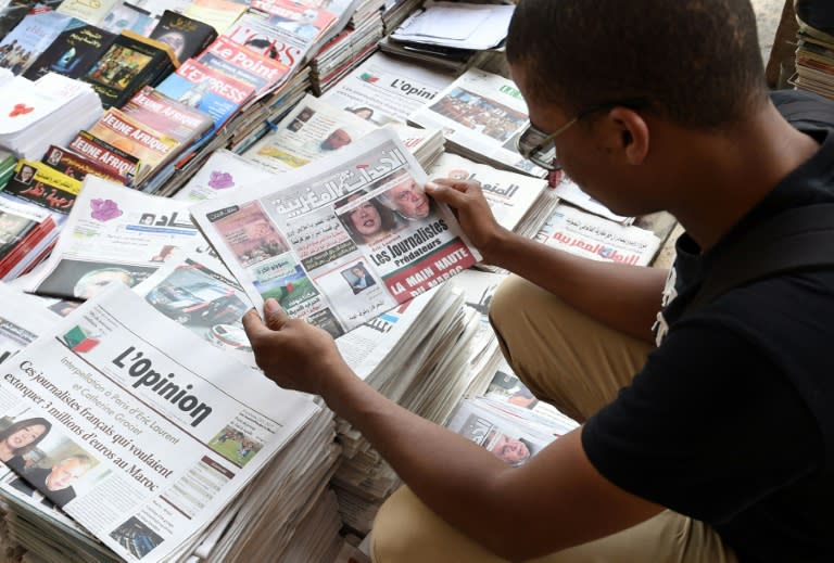 A Moroccan man looks at the cover of a daily newspaper showing portraits of the two French investigative journalists who have been charged in Paris with trying to blackmail the king of Morocco