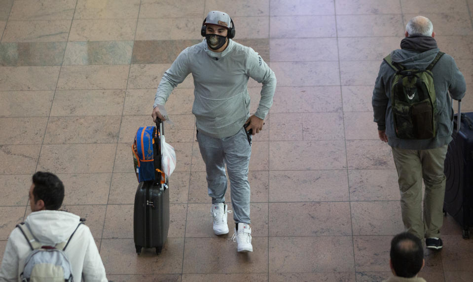 A man wears a protective mask as he wheels his luggage in the main terminal of Brussels International Airport in Brussels, Friday, March 13, 2020. European Union interior ministers on Friday were trying to coordinate their response to the COVID-19 coronavirus as the number of cases spreads throughout the 27-nation bloc and countries take individual measures to slow the disease down. For most people, the new coronavirus causes only mild or moderate symptoms, such as fever and cough. For some, especially older adults and people with existing health problems, it can cause more severe illness, including pneumonia. (AP Photo/Virginia Mayo)