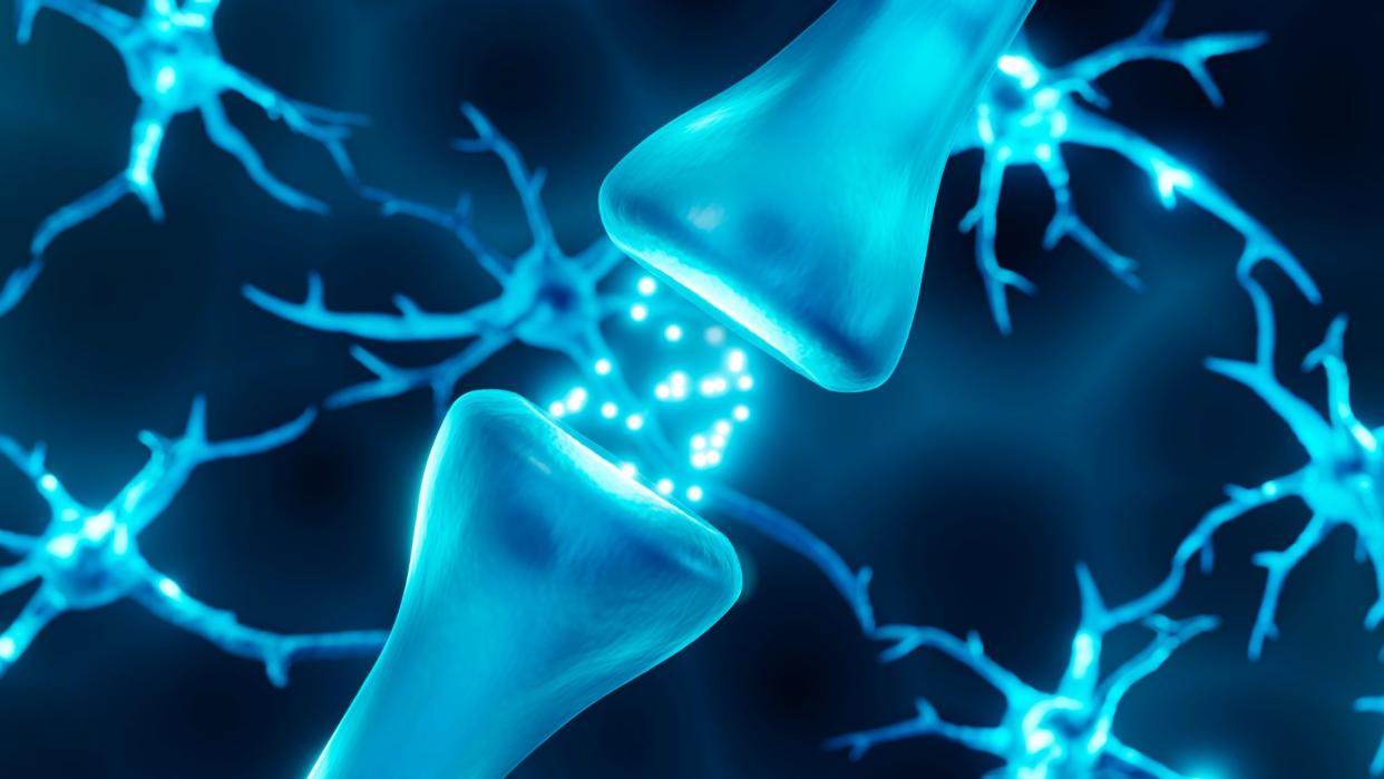  illustration of the gap between two neurons, with glowing spheres (representing neurotransmitters) passing between the cells 