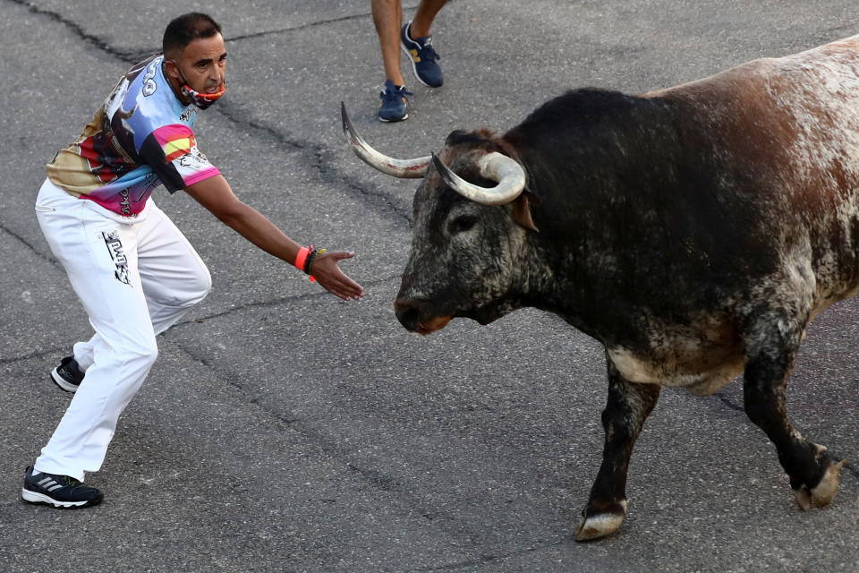 A reveller wearing a protective mask calls a steer during the first running-of-the-bull festival since the coronavirus disease (COVID-19) pandemic began in Villaseca de la Sagra, central Spain, September 5, 2021. REUTERS/Sergio Perez