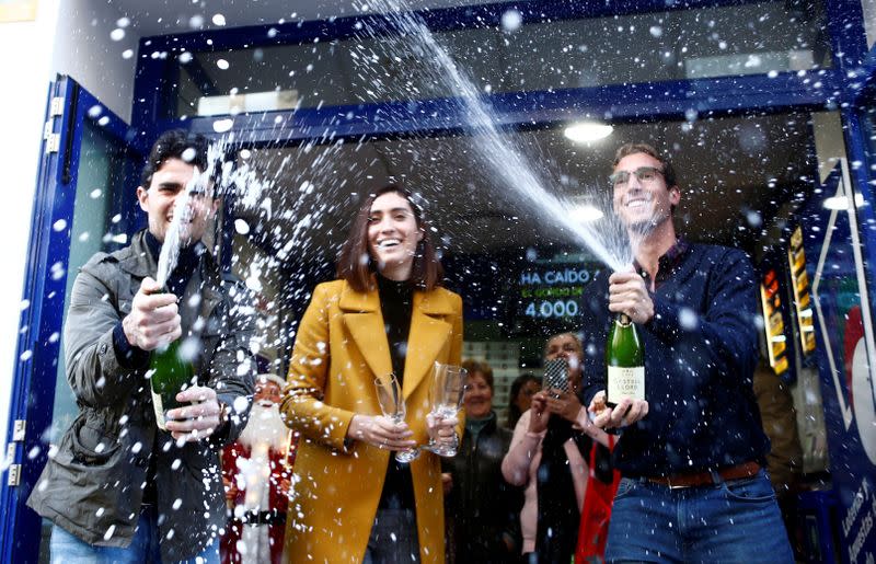 Foto de archivo: Juan, María and Miguel Ángel celebran fuera del quiosco que administran el haber vendido el premio mayor de la Lotería de Navidad en Ronda, España.