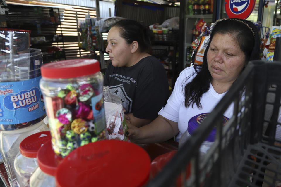 Maritza Pacheco, right, and her daughter Jennifer work at the small grocery store they opened four months prior, outside their home in the Primero de Diciembre neighborhood in Soyapango, El Salvador, Thursday, March 2, 2023. Before the government imposed a "state of exception" that imprisoned alleged gang members, Pacheco and her daughter secretly sold fruits and vegetables in a market in another neighborhood to scrape by, while her neighborhood was too dangerous and gangs charged hefty extortions. (AP Photo/Salvador Melendez)