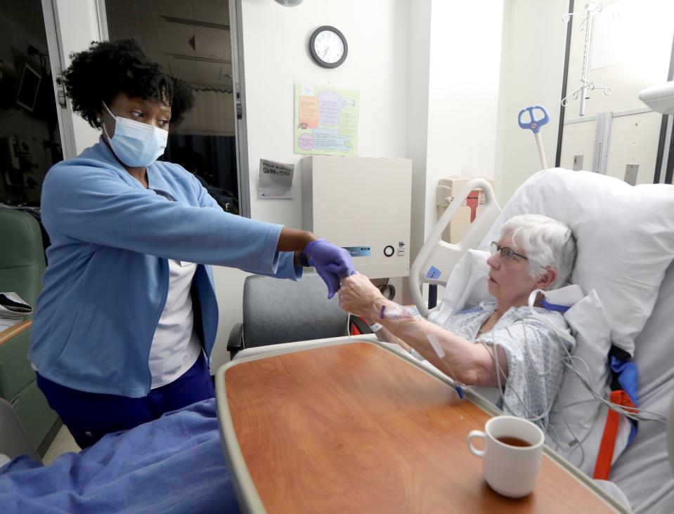 Vanessa Jean-Baptiste, a registered nurse in the intensive care unit at Northern Westchester Hospital in Mount Kisco, assesses patient Eileen McVeigh's motor strength at the start of her 12-hour shift on Feb. 28, 2022. Jean-Baptiste works three 12-hour shifts in the ICU each week as she has for more than a decade.
