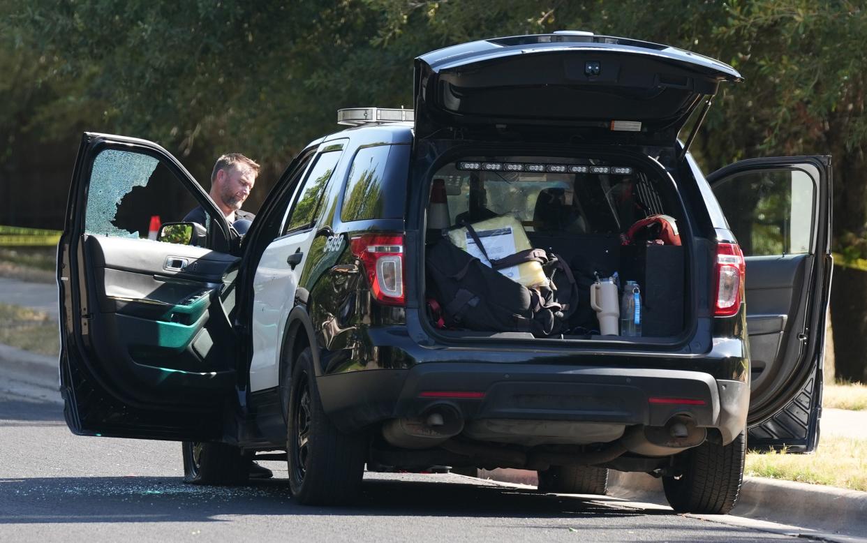 An investigator looks at a police vehicle with a broken window at the scene of a police shooting on Channel Island Drive in Southeast Austin on Aug. 7.