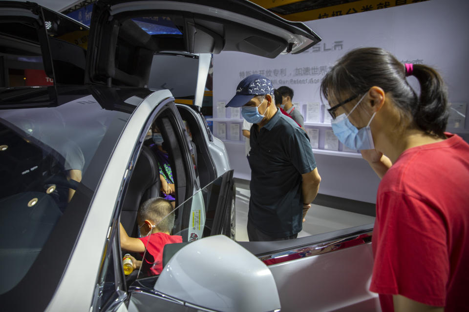 Visitors wearing face masks to protect against the coronavirus look at a Tesla vehicle on display at the China International Fair for Trade in Services (CIFTIS) in Beijing, Saturday, Sept. 5, 2020. Auto executives are flying in early to wait out a coronavirus quarantine ahead of the Beijing auto show, the year's biggest sales event for a global industry that is struggling with tumbling sales and layoffs. Organizers say they will impose intensive anti-disease controls on crowds and monitor visitors and employees for signs of infection. (AP Photo/Mark Schiefelbein)