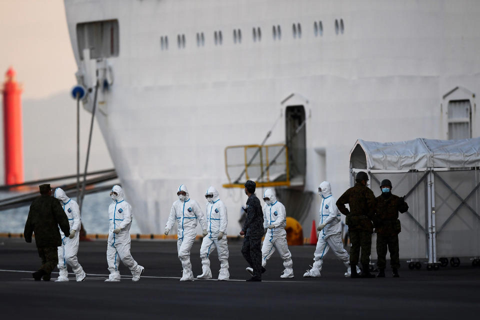 Image: People wearing protective suits walk from the Diamond Princess cruise ship, with around 3,700 people quarantined onboard due to fears of the new coronavirus, at the Daikoku Pier Cruise Terminal in Yokohama