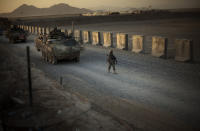 FILE - In this Aug. 8, 2009, file photo, U.S. soldiers from the 5th Striker Brigades walk next to armored vehicles as they arrive at their base on the outskirts of Spin Boldak, about 100 kilometers (63 miles) southeast of Kandahar, Afghanistan. President Joe Biden and his NATO counterparts bid a symbolic farewell to Afghanistan on Monday, June 14, in their last summit before America winds up its longest “forever war” and the military pulls out for good. (AP Photo/Emilio Morenatti, File)