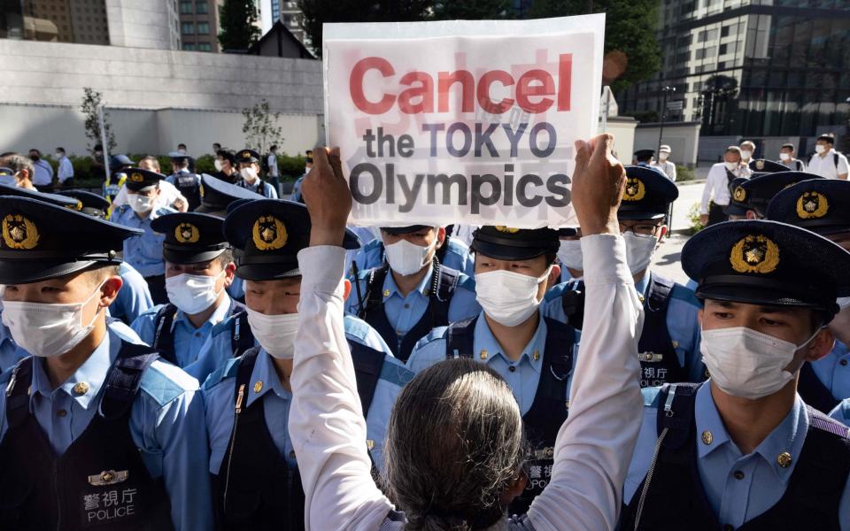 Police officers block a small group of activists as they walk towards the hotel where International Olympic Committee president Thomas Bach is staying for a demonstration in Tokyo on July 17, 2021, calling for the cancellation of the Tokyo 2020 Olympic Games - GETTY IMAGES