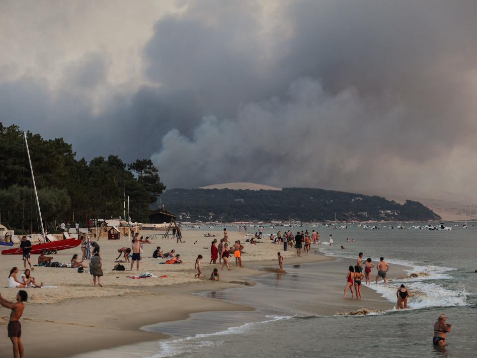 Smoke sits in the backdrop of beachgoers in France.
