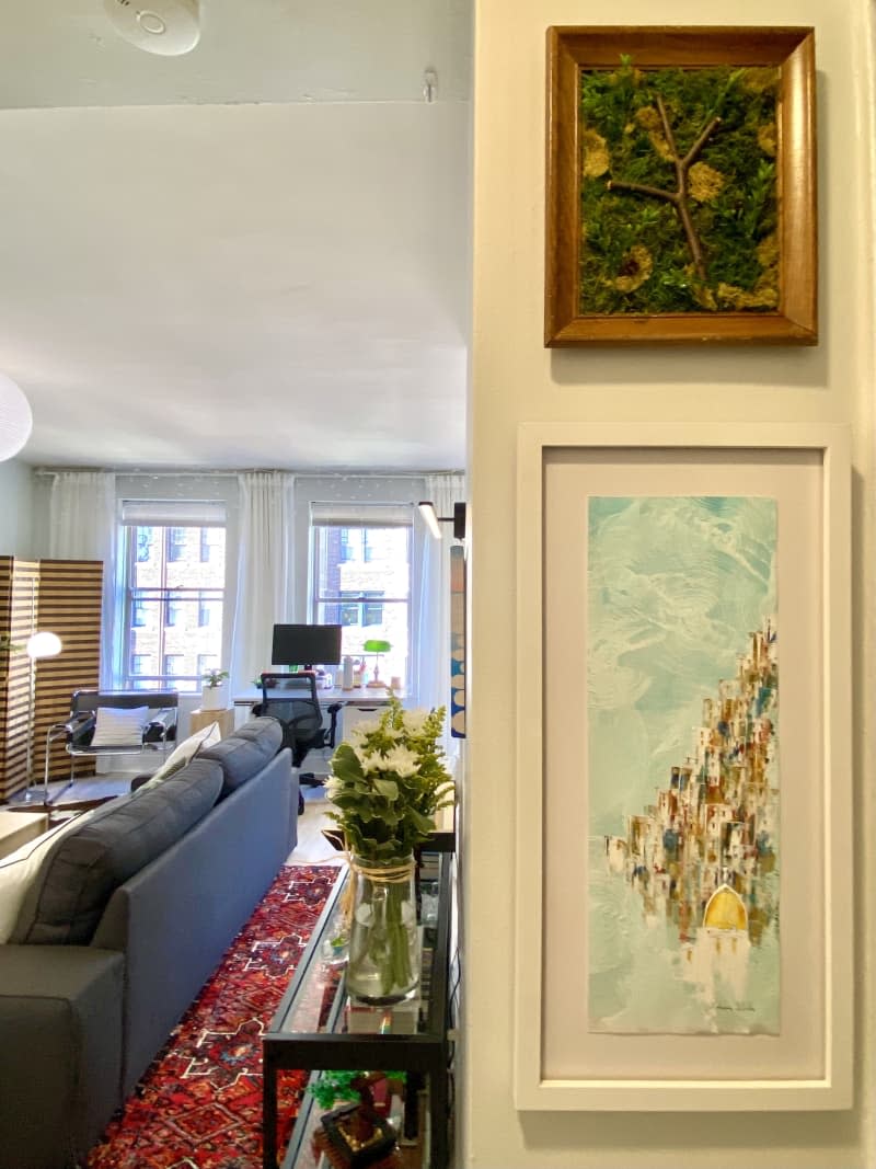 Hallway with white walls framed art and view of a living room.