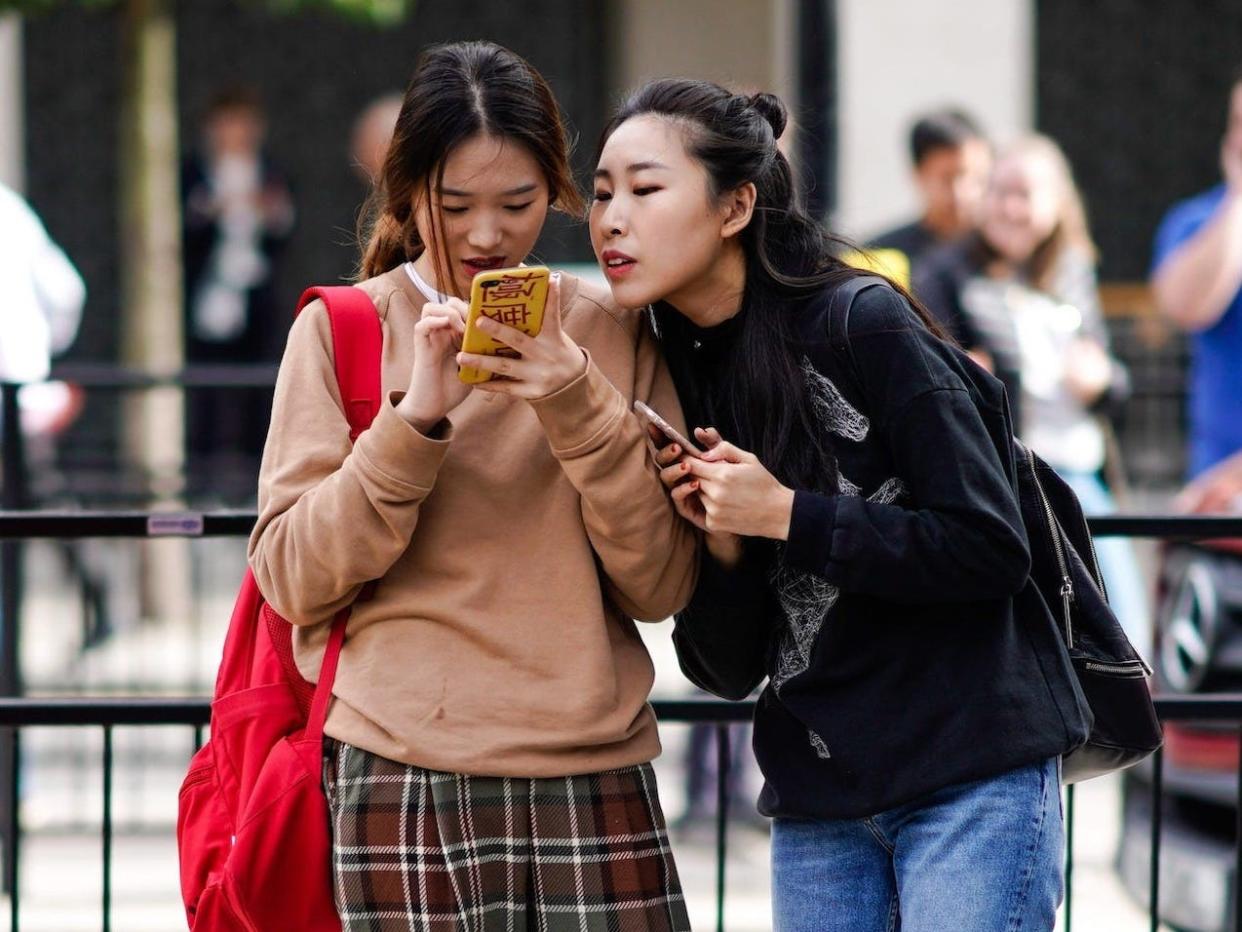 two girls calling cell phone texting