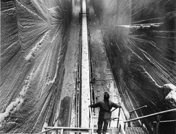 300 feet below street level, a worker supervises the conveyor belt as it carries chunks of rock salt towards the surface from the International Salt Mine, Detroit, Michigan. Photo taken by late Detroit Free Press Chief Photographer Tony Spina on January 14, 1971.