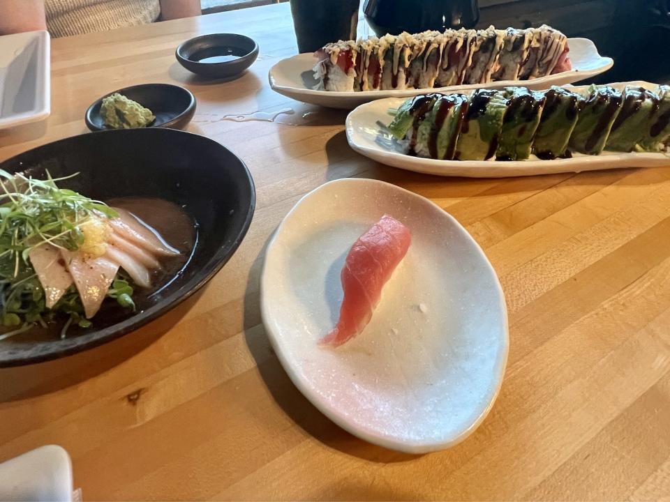 Plates of sushi on wooden restaurant table