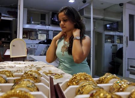 File Photo: A woman tries on a gold necklace inside a jewellery showroom at a market in Mumbai,, July 8, 2015. REUTERS/Shailesh Andrade