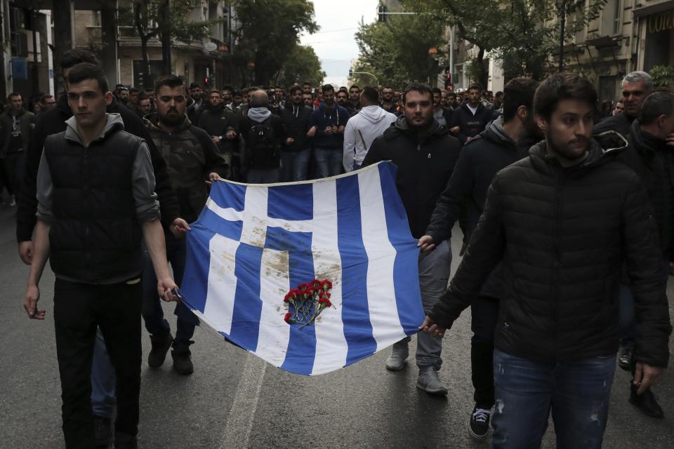 University students hold a blood-stained Greek flag from the deadly 1973 student uprising, in Athens, Saturday, Nov. 17, 2018. Several thousand people are expecting to march to the U.S. Embassy in Athens under tight police security to commemorate a 1973 student uprising that was crushed by Greece's military junta, that ruled the country from 1967-74. (AP Photo/Yorgos Karahalis)