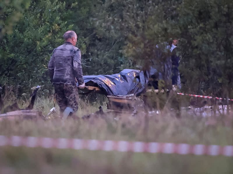 Especialistas en emergencias transportan una bolsa para cadáveres cerca de los restos del avión privado vinculado al jefe de los mercenarios de Wagner, Yevgeny Prigozhin, en el lugar del accidente, en el óblast de Tver, Rusia