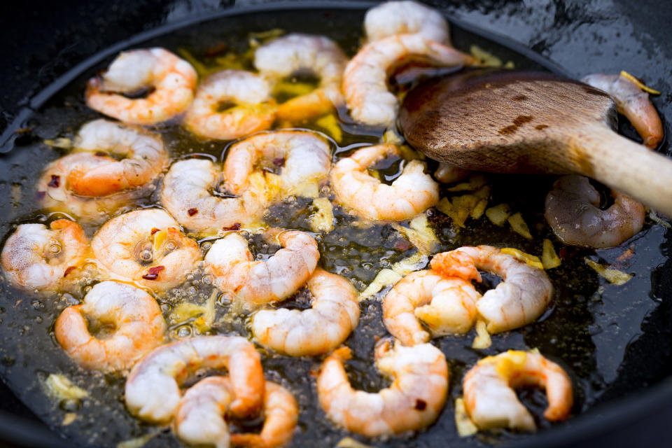 Fresh prawns frying in olive oil with garlic and chili.