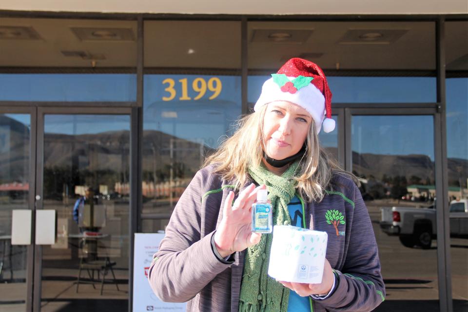 Stephanie Hale of Thrive of Southern New Mexico hold up toilet paper and hand sanitizer giveaways at Thrive's toy drive to support Toys for Tots of Otero County December 4, 2020.