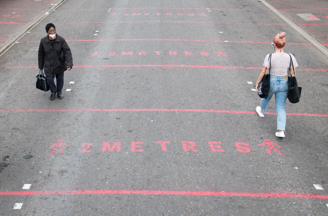 People walk over two metre social distancing markings at Ridley Road street market in east London, as the government considers relaxing official guidelines on social distancing to a shorter distance of one metre. Health Secretary Matt Hancock, pressed to reduce social distancing from two metres to one metre, has told the Commons: "It's the sort of thing of course we want to lift and we need to do that in a way that is careful and safe.