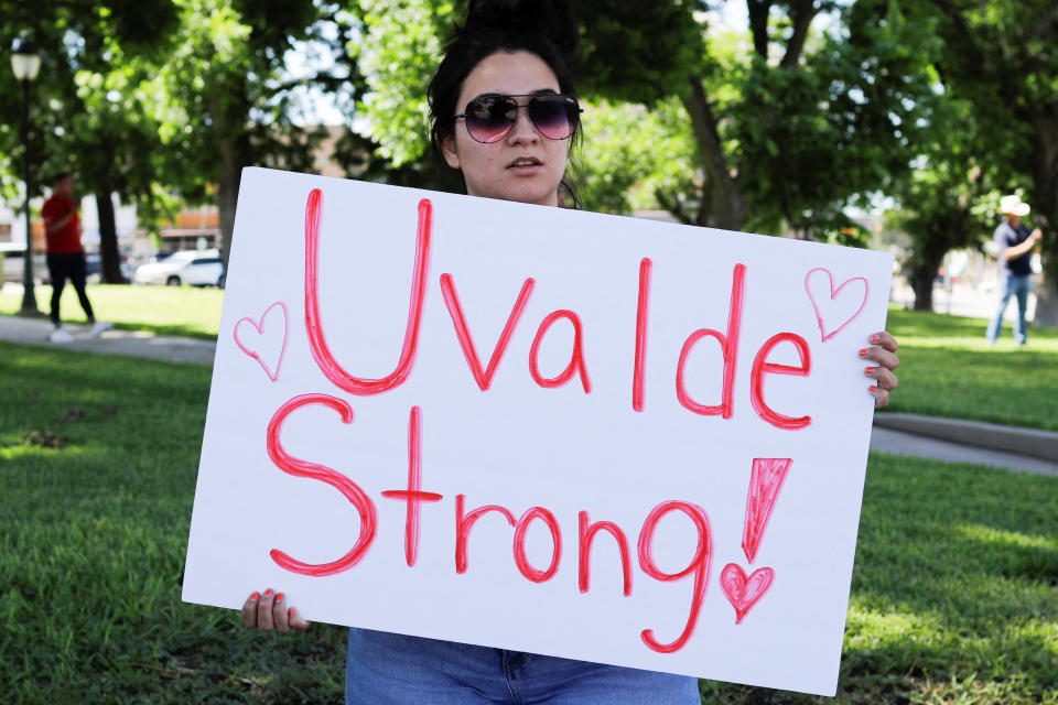 Una mujer muestra su apoyo a las víctimas mientras sostiene un letrero frente a la Robb Elementary School. REUTERS/Marco Bello.