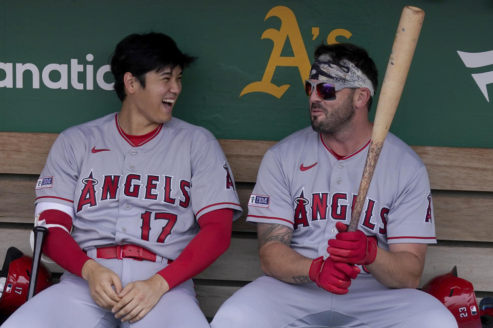 Los Angeles Angels' Shohei Ohtani (17) laughs in the dugout with Mike Moustakas before a baseball game against the Oakland Athletics in Oakland, Calif., Saturday, Sept. 2, 2023. (AP Photo/Jeff Chiu)