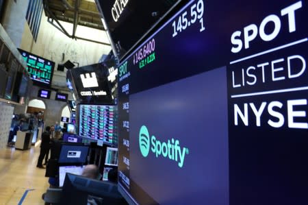 A screen displays the company logo and trading info for Spotify on the floor at the NYSE in New York