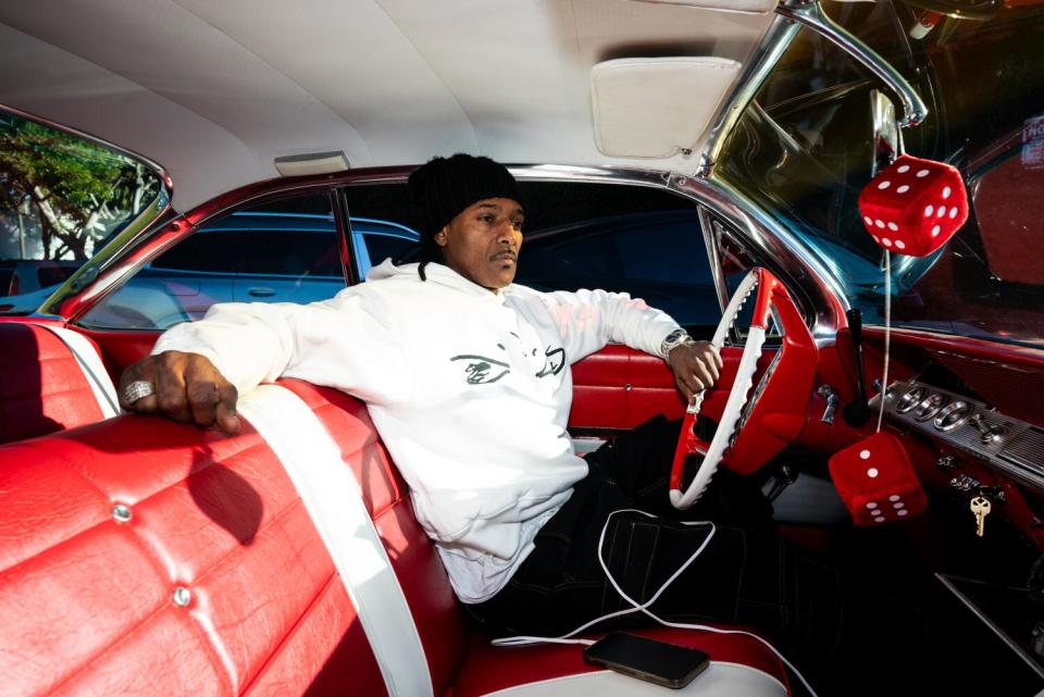 A rapper sits in the front seat of a car