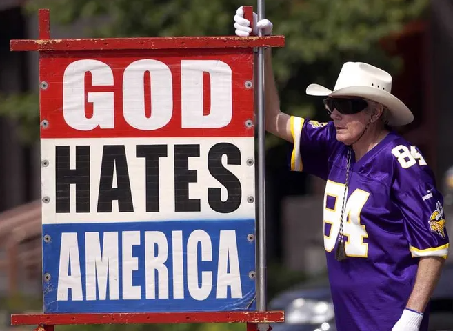 This Topeka Capital-Journal file photo shows Fred W. Phelps Sr. displaying one of the signs he held while conducting anti-gay picketing with members of his congregation at Topeka's Westboro Baptist Church.