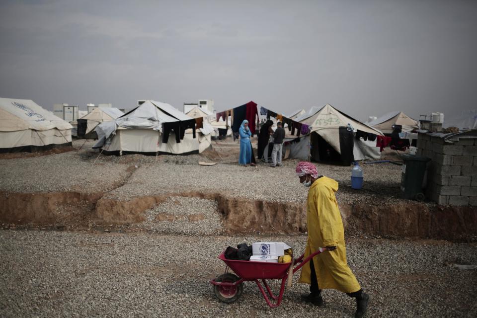 A worker carried aid supplied at a camp for people displaced by fighting between security forces and Islamic State militants east of Mosul, Iraq, Wednesday, Feb. 15, 2017. The United Nations says they are temporarily pausing aid operations to neighborhoods in eastern Mosul retaken from the Islamic State group for security reasons as IS insurgent and counter attacks continue to inflict heavy civilian casualties there.(AP Photo/Bram Janssen)