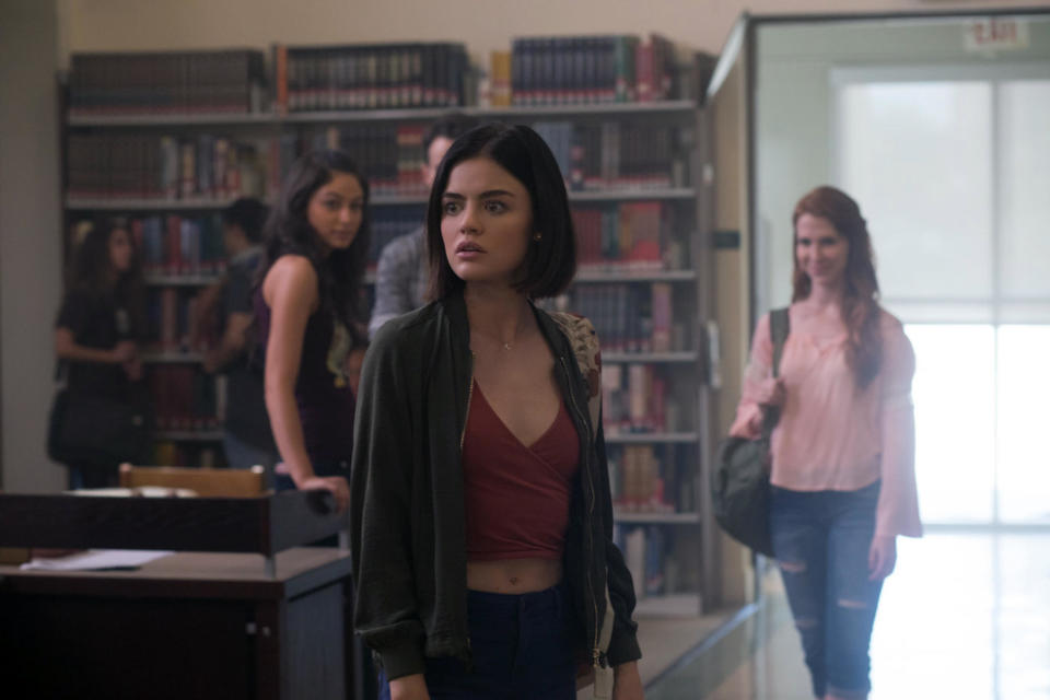 A young woman stares concerningly around a library full of smiling strangers