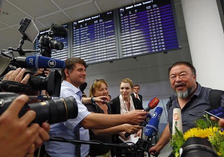 Dissident Chinese artist Ai Weiwei (R) is surrounded by media as he arrives at the airport in Munich, Germany July 30, 2015. REUTERS/Michaela Rehle