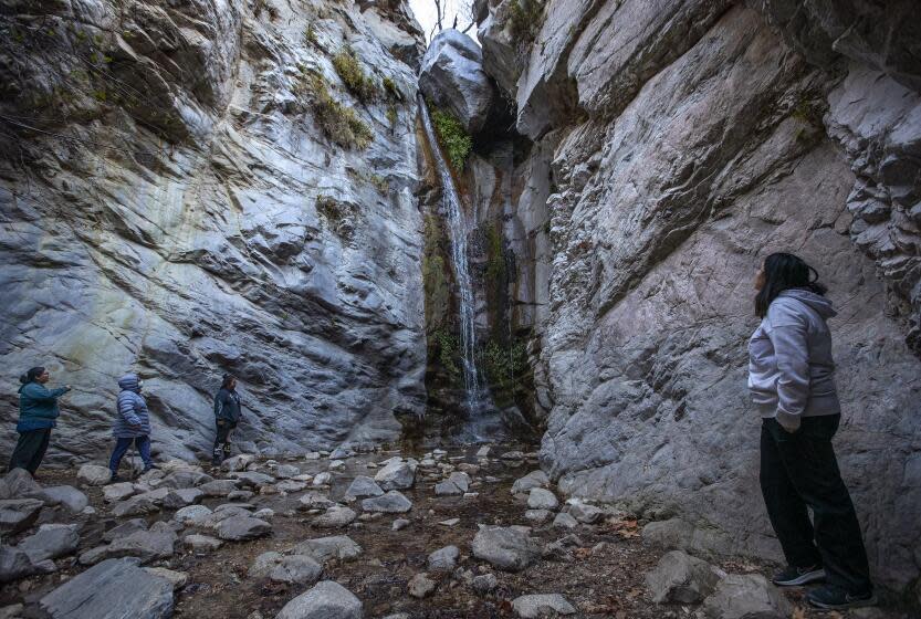 ALTADENA, CA-DECEMBER 16, 2023:Samantha Alvarez, right, of Boyle Heights, stands near a 50 foot tall waterfall after hiking on the trail to Millard Falls at the base of the San Gabriel Mountains near Altadena. There are efforts to expand existing national monuments in California and add new ones. (Mel Melcon / Los Angeles Times)