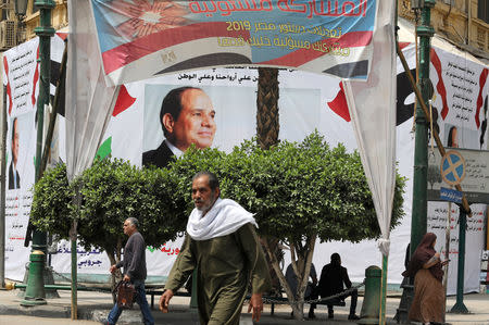 Pedestrians walk in front of a banner of the Egyptian President Abdel Fattah al-Sisi before the upcoming referendum on constitutional amendments in Cairo, Egypt April 16, 2019. REUTERS/Mohamed Abd El Ghany