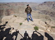 File - In this May 6, 2011, file photo, Swiss adventurer Yves Rossy, who calls himself the JetMan, stands on the ledge of the Grand Canyon on Guano Point on the Hualapai Indian Reservation to speak to the media. When actor Will Smith turns 50 on Tuesday, Sept. 25, 2018, he will jump head-first into the big milestone. The “Fresh Prince” plans to bungee jump from a helicopter over a gorge just outside Grand Canyon National Park. His birthday activity is the latest in a vast history of outrageous stunts staged in and around one of the world’s seven natural wonders. (AP Photo/Matt York, File)