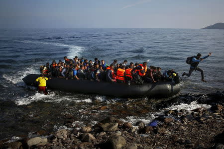 An Afghan migrant jumps off an overcrowded raft onto a beach at the Greek island of Lesbos October 19, 2015. REUTERS/Yannis Behrakis