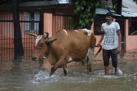 A man walks his cow through a waterlogged street during heavy monsoon rains in Mumbai
