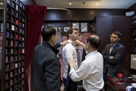 Tailors measure a customer inside a bespoke tailoring firm at Hong Kong's Tsim Sha Tsui shopping district February 14, 2015. REUTERS/Tyrone Siu