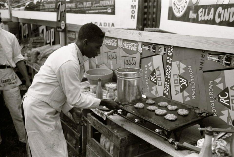 Hombre cocinando hamburguesas en un restaurante en la ciudad de Crowley, Luisiana, en 1938.