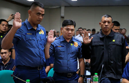 Philippines National Police (PNP) officers Jeremias Pereda, Jerwin Cruz and Arnel Oares take an oath during a hearing on the killing of 17-year-old high school student Kian Delos Santos in a recent police raid, at the Senate headquarters in Pasay city, metro Manila, Philippines August 24, 2017. REUTERS/Romeo Ranoco