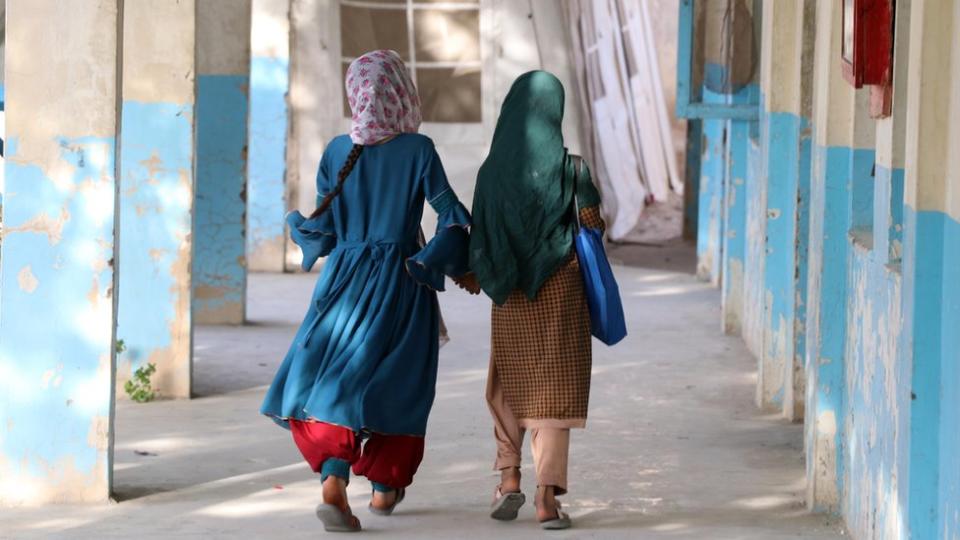 Two Afghan girls walking to a school building in Kandahar in September 2022