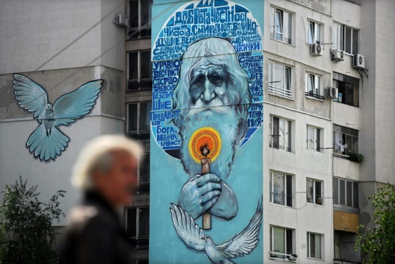 Street artists painted a huge image of the white-haired man holding a candle on the facade of an apartment building in Sofia