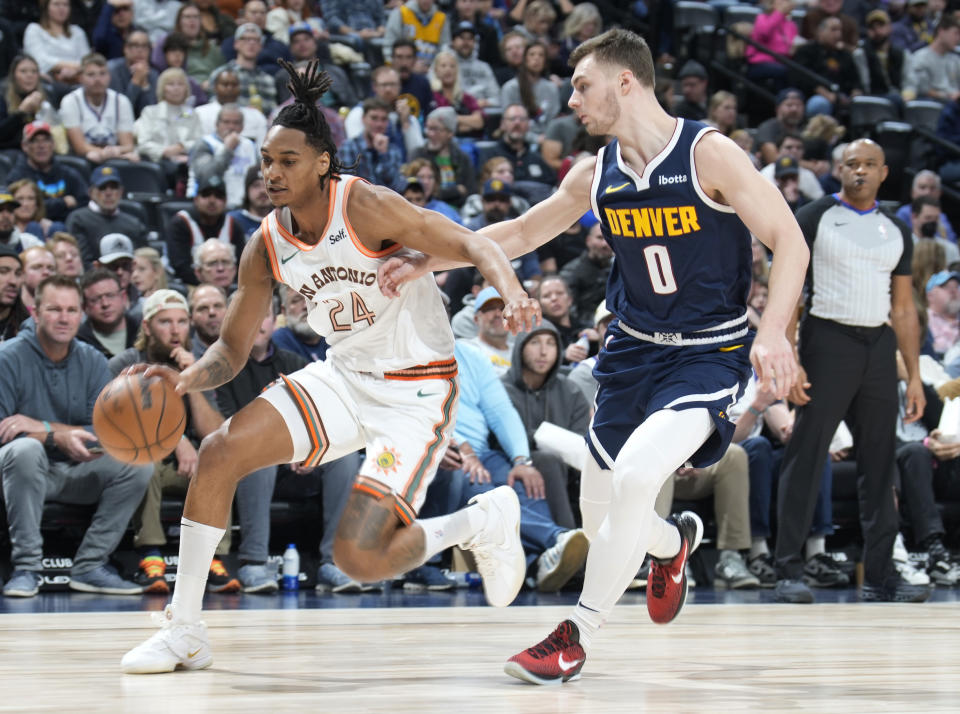 San Antonio Spurs guard Devin Vassell, left, drives to the basket as Denver Nuggets guard Christian Braun, right, defends in the first half of an NBA basketball game Sunday, Nov. 26, 2023, in Denver. (AP Photo/David Zalubowski)