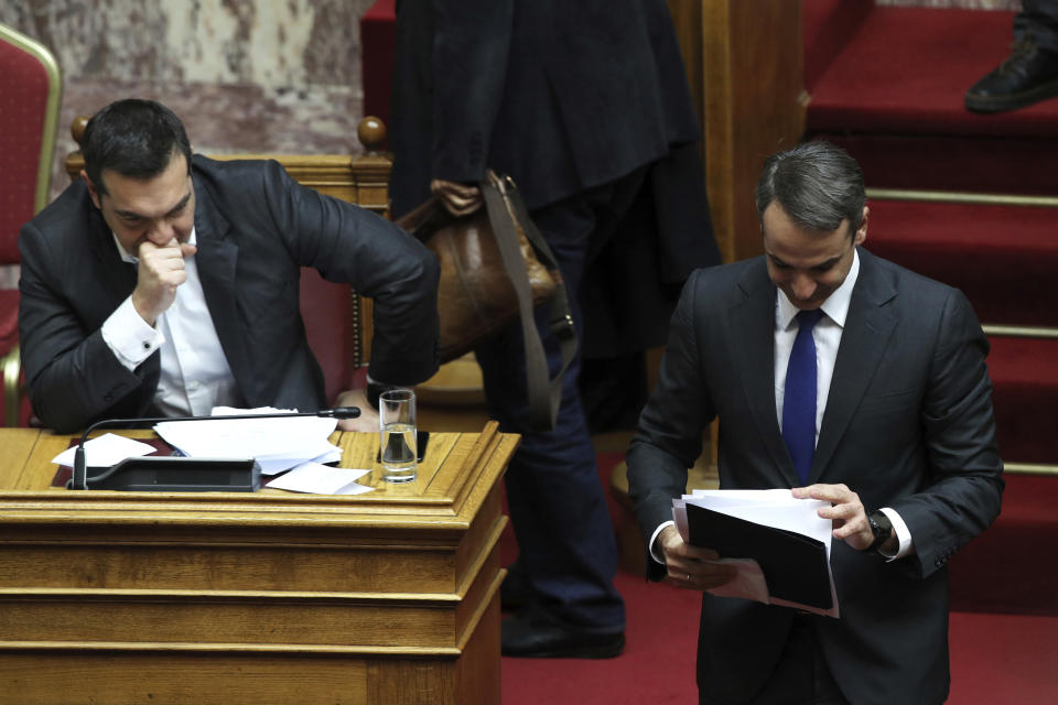 New Democracy party leader Kyriakos Mitsotakis, right, leaves after finishing his speech as he walks in front of Greek Prime Minister Alexis Tsipras, during a parliamentary session in Athens, on Tuesday, Jan. 15, 2019. Greece's prime minister is defending his deal to normalize relations with neighboring Macedonia ahead of a confidence vote in parliament after his governing coalition collapsed over the agreement. (AP Photo/Petros Giannakouris)