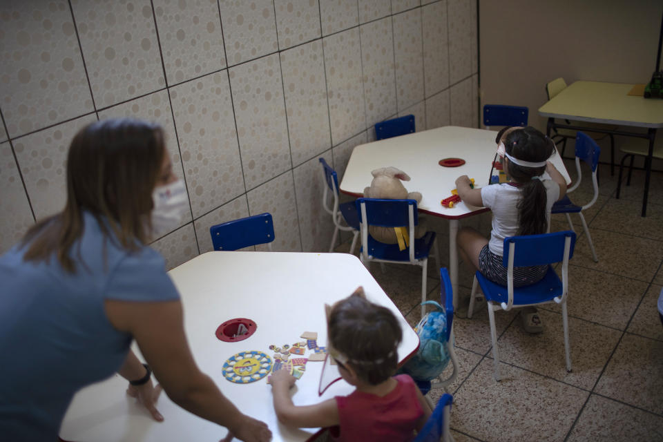 Children wearing face shields as a precaution against the new coronavirus outbreak sit spaced apart in individual tables at the Pereira Agustinho daycare, nursery school and pre-school, after it reopened amid the new coronavirus pandemic in Duque de Caxias, Monday, July 6, 2020. The city of Manaus in the Amazon rainforest and Duque de Caxias in Rio de Janeiro’s metropolitan region, became on Monday the first Brazilian cities to resume in-person classes at private schools since the onset of the COVID-19 pandemic, according to the nation's private school federation. (AP Photo/Silvia Izquierdo)