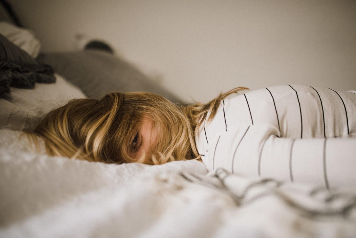 Woman lying in bed with eyes open but drowsy