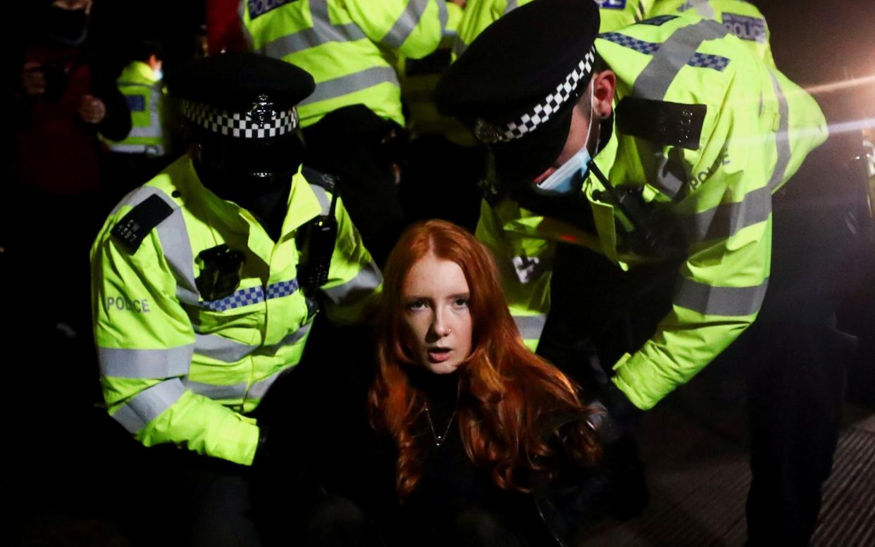 Police detain a woman as people gather at a memorial site in Clapham Common Bandstand, following the kidnap and murder of Sarah Everard - Reuters