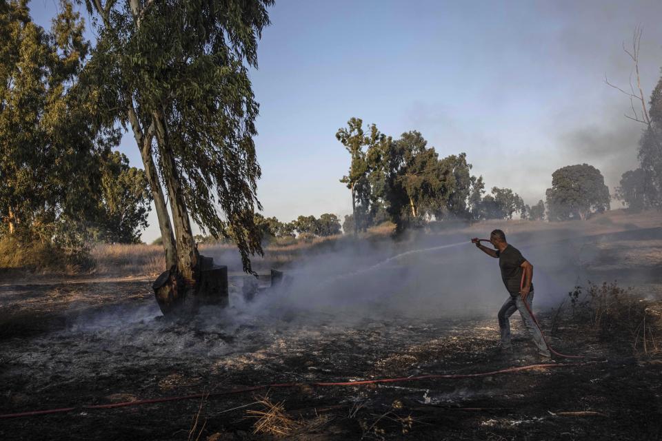 An Israeli man works at the site of a fire on the Israeli side of the border between Israel and Gaza, Friday, Aug. 21, 2020. The Israeli military says Palestinian militants fired 12 rockets at Israel from the Gaza Strip overnight, nine of which were intercepted. (AP Photo/Tsafrir Abayov)