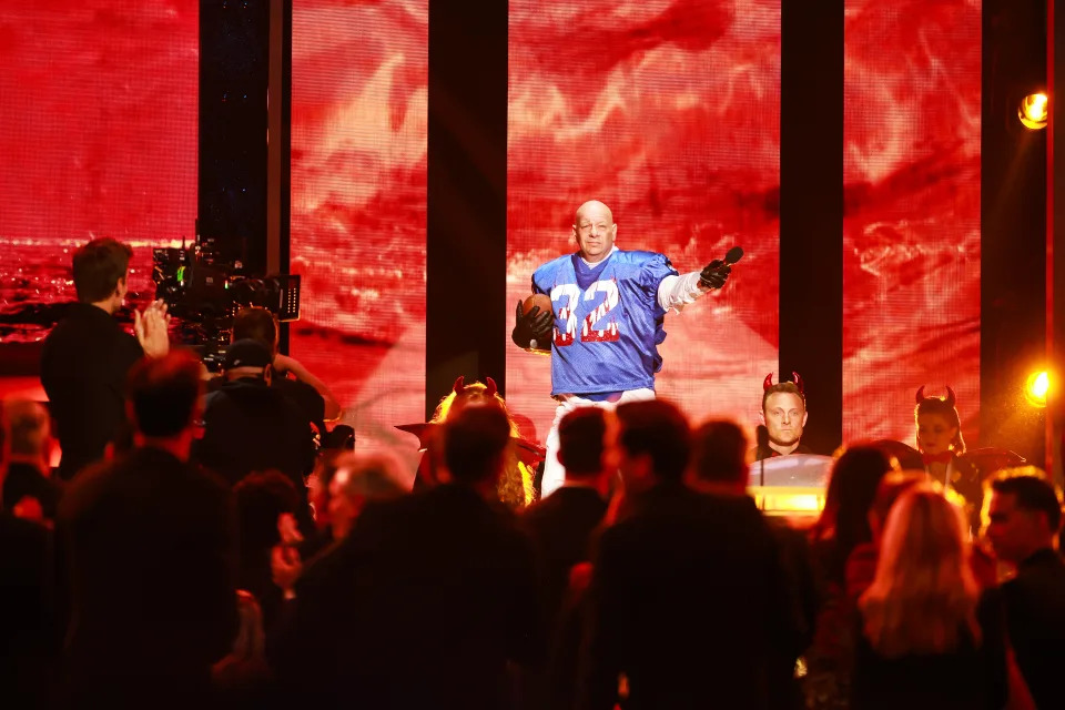 Jeff Ross veste uma camisa de futebol americano no palco.